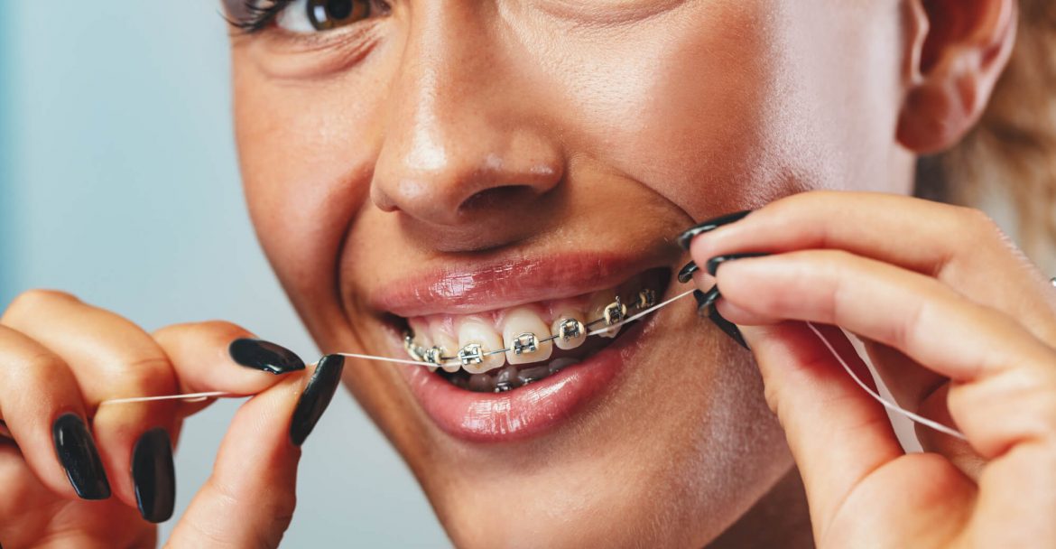 a woman with braces flossing teeth as instructed by her Dentist in midtown Manhattan